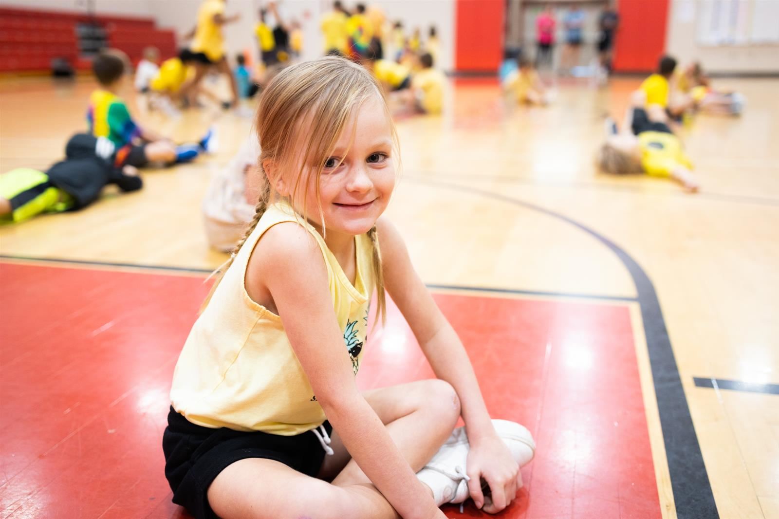 Girl smiling in PE class while sitting on gym floor